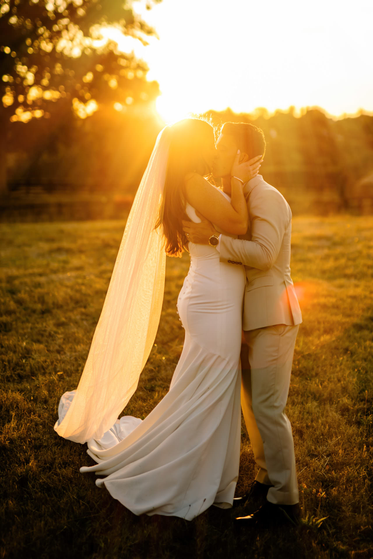 Golden hour wedding photo of bride and groom kissing