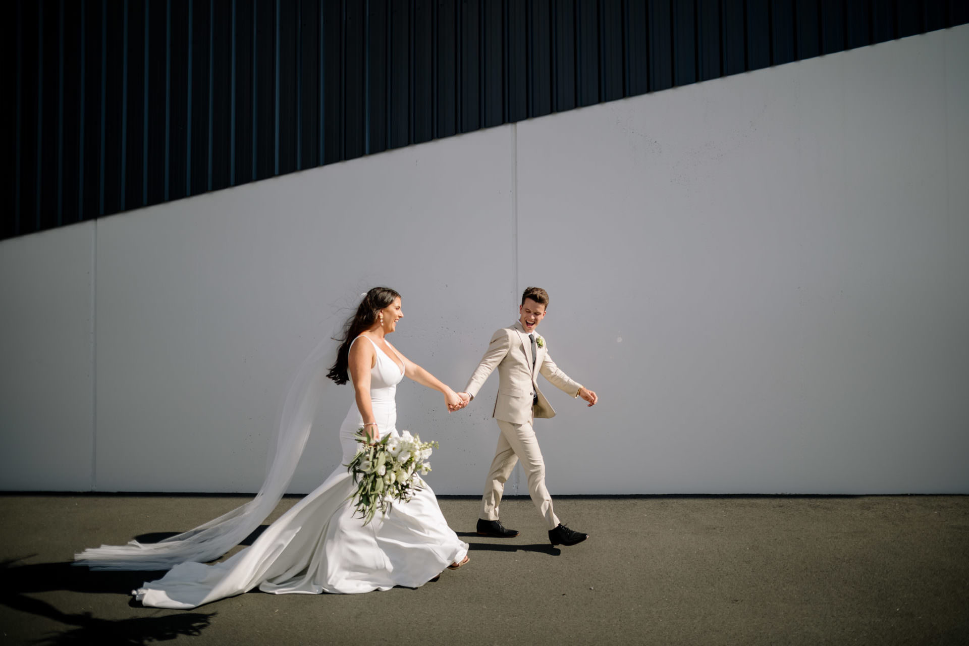 Waikato wedding photograph of bride and groom walking accross black and white wall