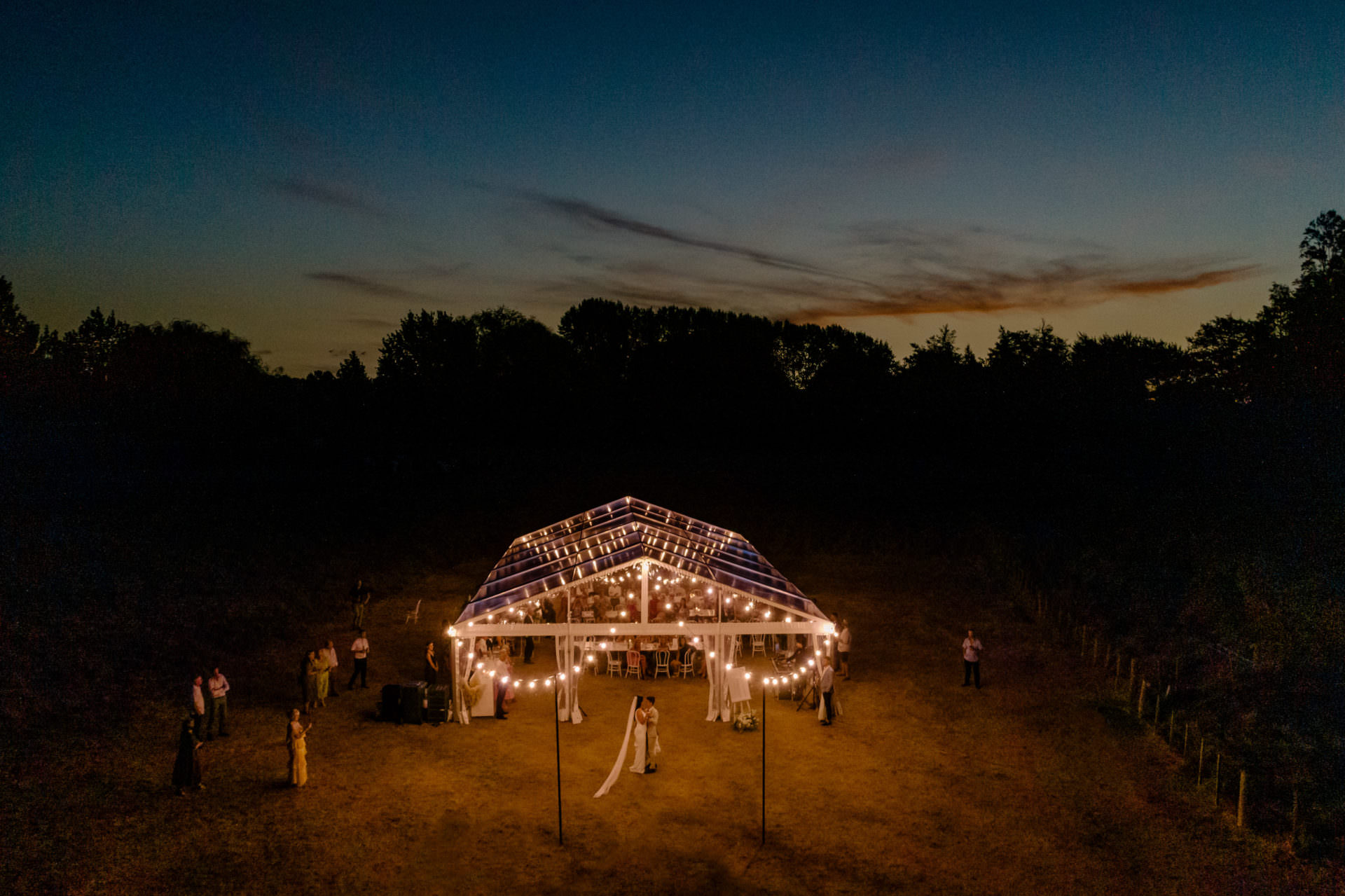 twelve tables clear marquee at night with festoons